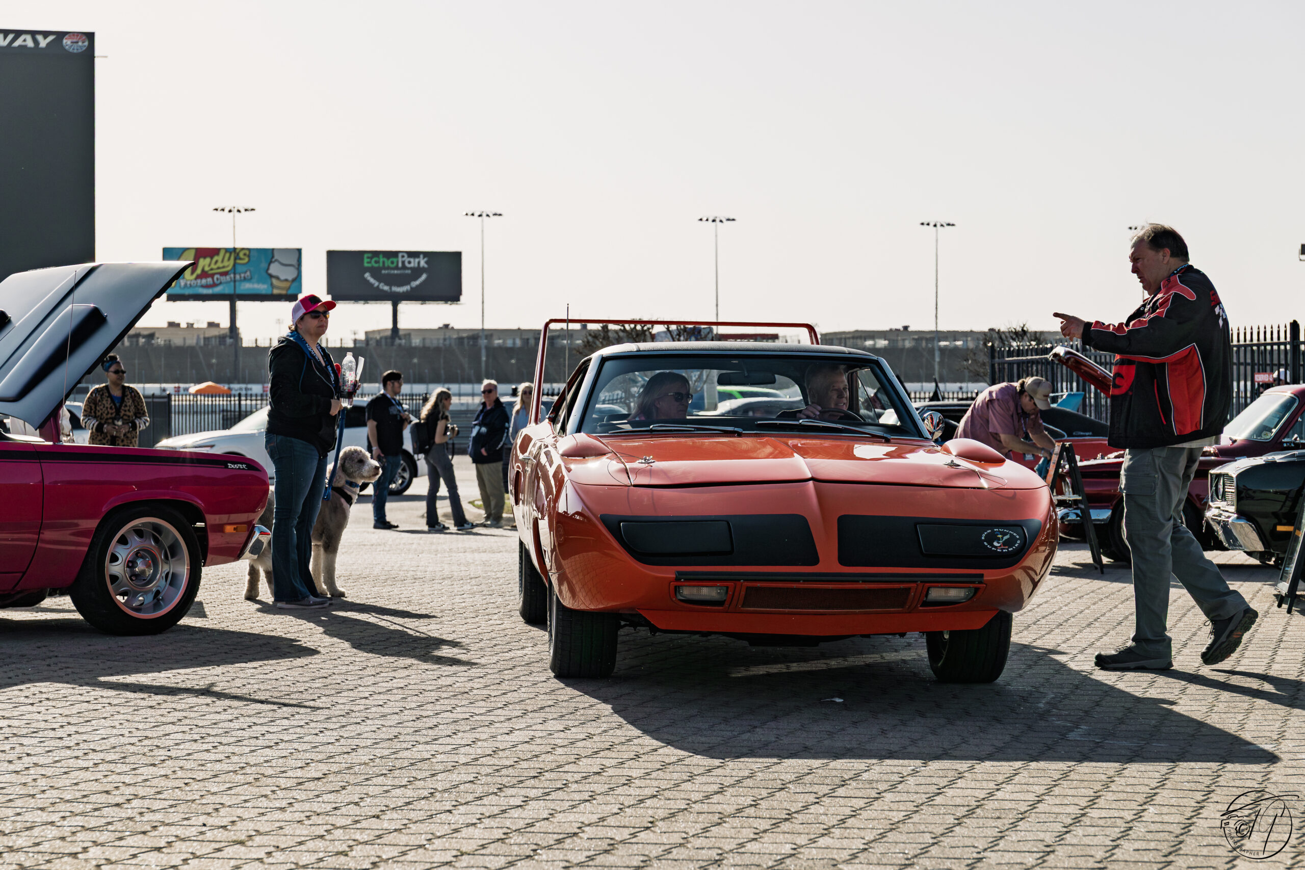 Red muscle car with fans at the show